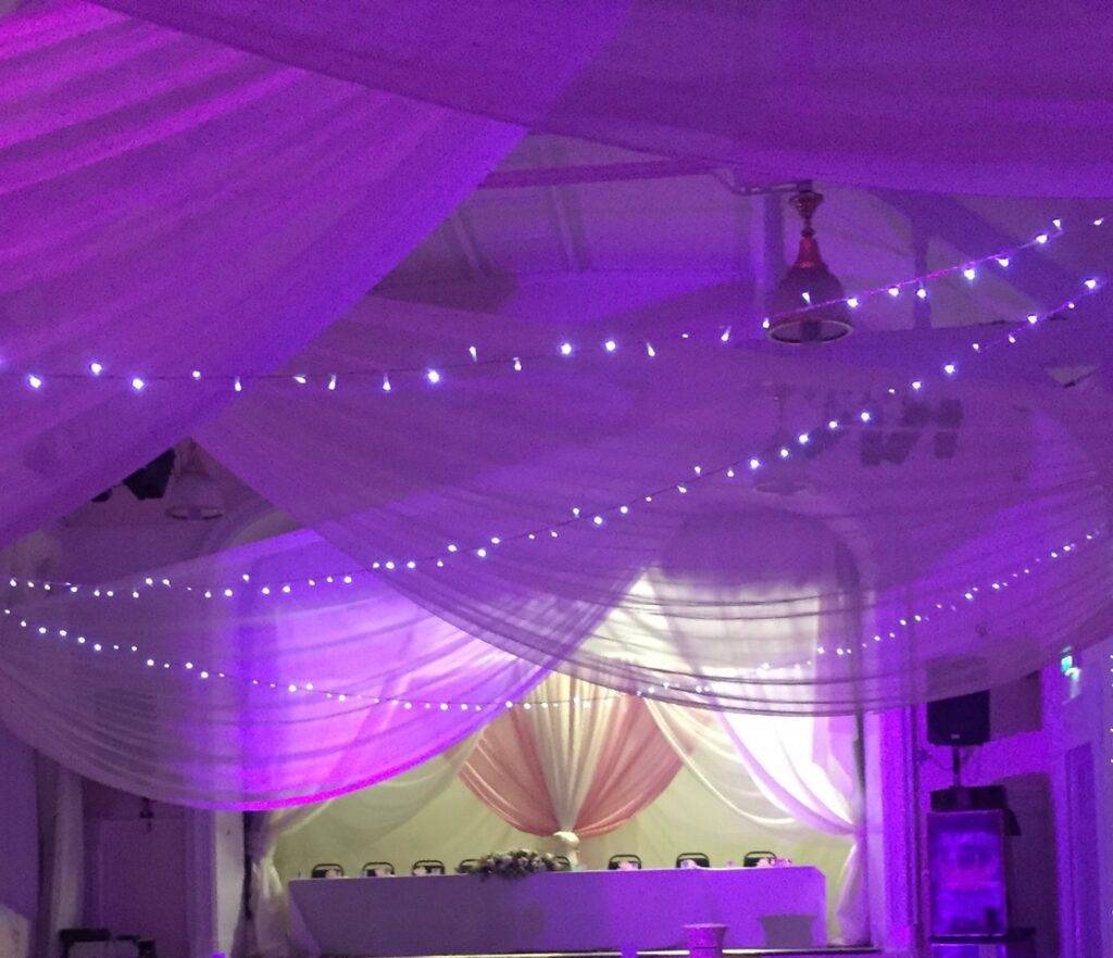Venue draping with fairy lights and purple Uplight
